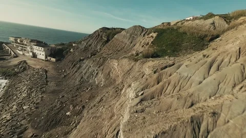 Waves crash against rugged, rocky cliffs beneath a clear sky Video stock 341825811