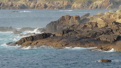Waves crash against rugged rocky formations along the coastline at Praia De Stock Footage 346713018