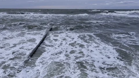 Waves crash against a sturdy jetty in turbulent seas, creating a dramatic scene Stock Footage 304729920