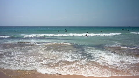 Waves crash in on a beach in summer as people swim and surf Stock Footage 245212867