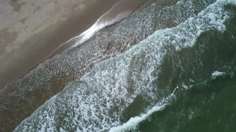 Waves crash on the beach in summer as sunlight reflects off the shiny sand, Stock Footage 312632887