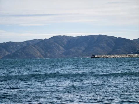 Waves Crash Beneath Distant Mountains, Vast Ocean Landscape With Shifting Teal Stock Photos