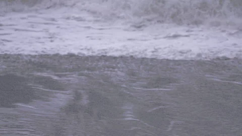 Waves crash at a black sand beach in Vik during changing water patterns Video stock 327082596