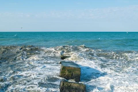 Waves crash on breakwaters. Stock Photos