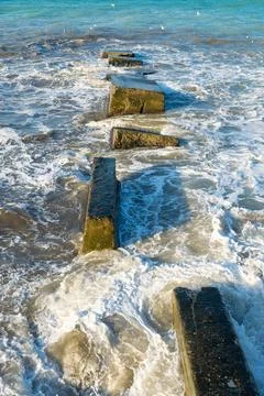 Waves crash on breakwaters. Stock Photos