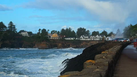 Waves crash dramatically against the rocks and seawall as storm watchers gather Видео 328956587