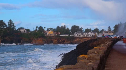 Waves crash dramatically against the rocks and seawall as storm watchers gather Видео 328957715