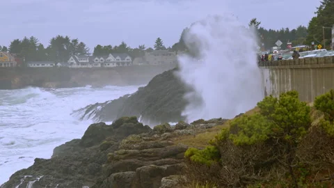 Waves crash dramatically against the rocks and seawall as storm watchers gather Видео 329144670