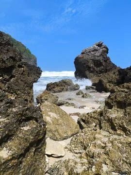 Waves crash gently against rugged stone formations 库存照片