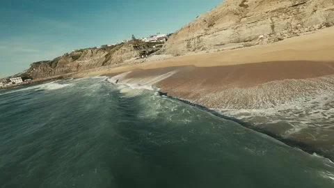Waves crash onto golden sands below steep cliffs Stock Footage 341825704