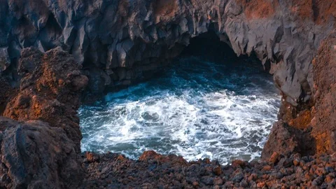 Waves crash inside a rocky volcanic cave in Los Hervidores Lanzarote Stock Footage 89145214