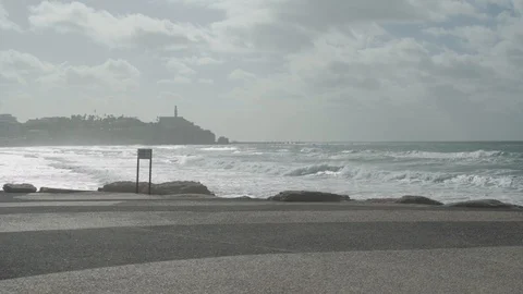Waves crash next to promenade with old city in background Stock Footage 100705187