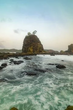 Waves crash over rugged rocks at Watu Lumbung Beach in Yogyakarta. Stock Photos
