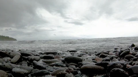 Waves crash over stony beach in handheld low angle, slow motion 4K Video stock 98426132