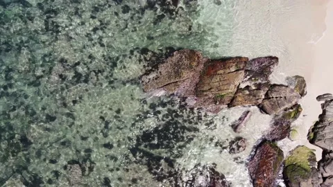 Waves crash on the rocks of a beach on clear water Stock Footage 169096310