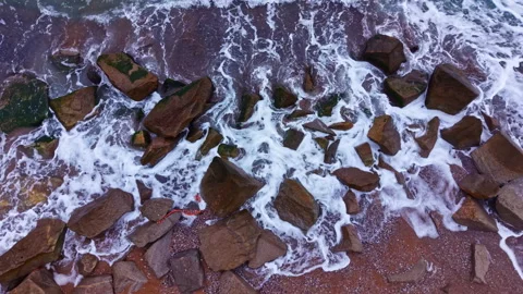 Waves crash on rocks at the shoreline under gray skies during the late afternoon Stock Footage 335394914