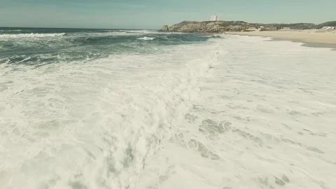 Waves crash on sandy beach, creating white foam Stock Footage 341822556