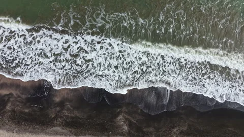 Waves crash on sandy beach during daytime with birds flying above and clouds Stock Footage 336487669