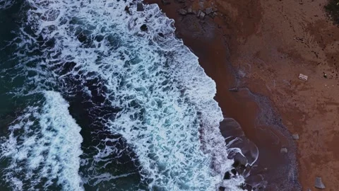 Waves crash on sandy beach near rocky shore during sunny day Vidéo 331297780