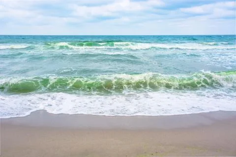 Waves crash on sandy beach Stock Photos
