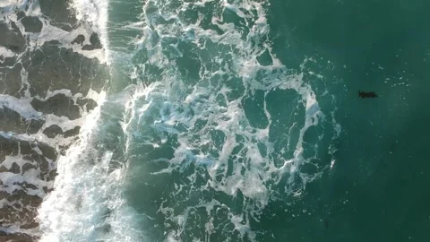 Waves crash on a sandy beach sea foam and blue water near coastline in top view 動画素材 245209934