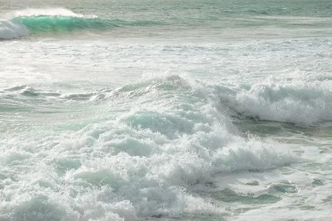 Waves crash on sandy beach, sunset with an empty shoreline and gentle breeze Stock Photos
