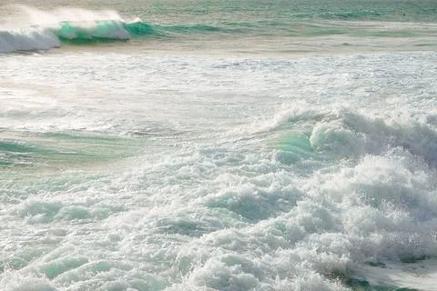 Waves crash on sandy beach, sunset with an empty shoreline and gentle breeze Stock Photos