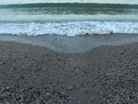 Waves crash on a sandy beach as the tide rolls in during early morning at the 스톡 사진
