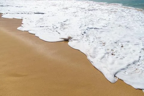 Waves crash on sandy beach under sunny sky, creating beautiful scene Stock-Fotos