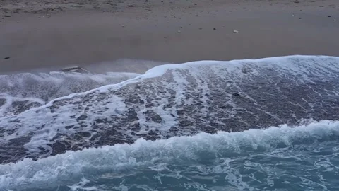Waves crash onto sandy shore at sunset in a serene coastal landscape Stock Footage 294249247