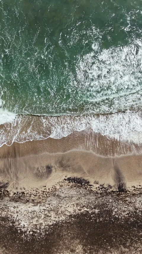 Waves crash on sandy shore as water meets land at the beach during a sunny day Stock Footage 337929257