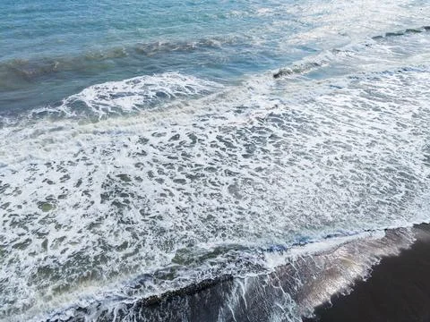 Waves crash on the shore at a beach during the day with bright sunlight ref.. Stock Photos