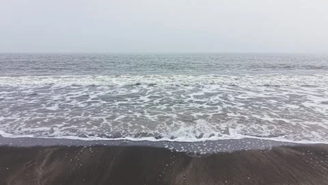 Waves crash on the shore as clouds fill the sky at the beach during morning Stock Footage 336602150
