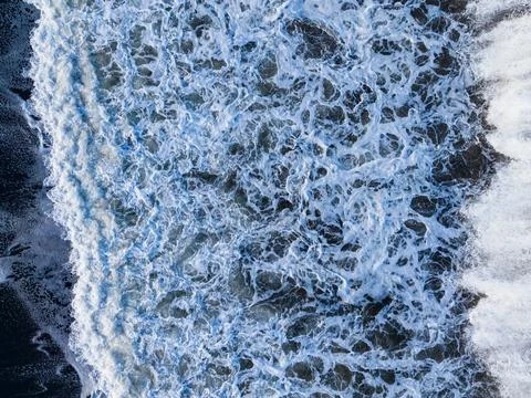 Waves crash into the shore creating foam and splashes during the day at a c.. Stock Photos