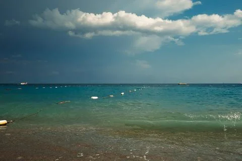Waves crash on shore, creating foam as dark clouds fill the sky above. Boats Stock Photos