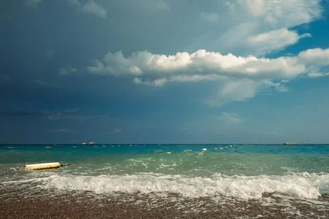 Waves crash on shore, creating foam as dark clouds fill the sky above. Boats Stock Photos