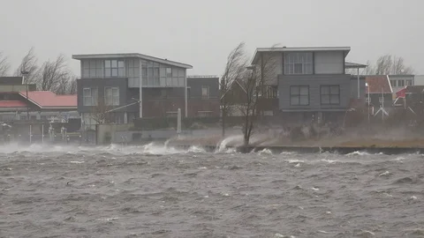 Waves crash on shore in front large houses on river in the Netherlands Stock Footage 85416841