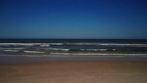 Waves crash on the shore at an ocean beach during a clear afternoon Stock Footage 339938644