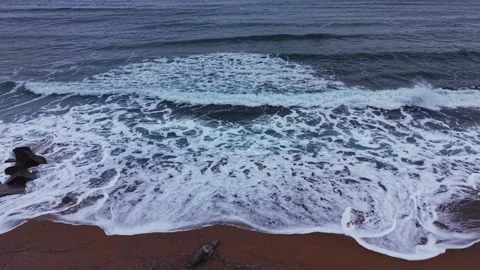 Waves crash on the shore with rocks during a cloudy day at the beach Vidéo 331296377