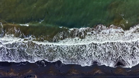 Waves crash on the shore as sunlight reflects on the green ocean during midday Stock Footage 331156048