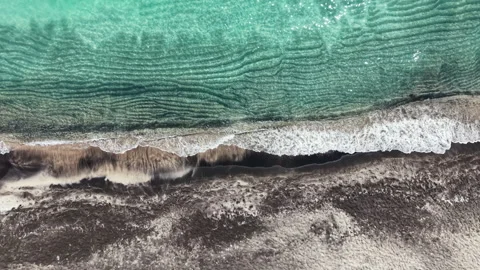 Waves crash on the shore while the sun shines over the sandy beach and clear Stock Footage 337889318