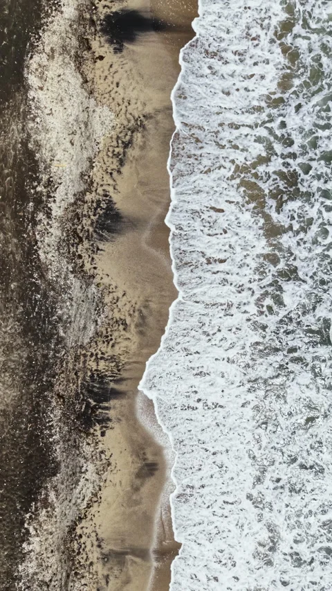Waves crash on the shoreline at a beach with sand and water mingling during the Stock Footage 339498485