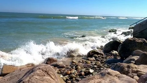 Waves crash at Ventura Beach as surfer comes in Stock Footage