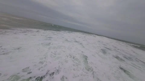 Waves crash with white foam against wet sand under overcast skies Stock Footage 345050907