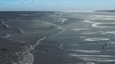 Waves crash onto wide, wet sand Stock Footage 346261260