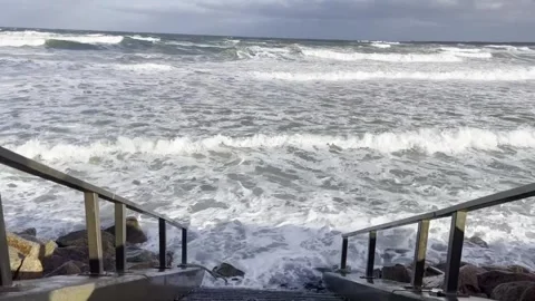 Waves crashing  against the beach stone steps Stock Footage 287114164