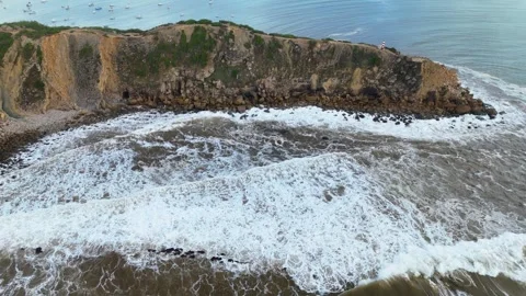 Waves crashing against coastal cliffs near tranquil waters and boats Stock Footage 287992524