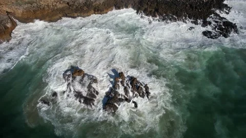 Waves crashing against jagged rocks in green sea in Cascais, Portugal Stock Footage 224912893