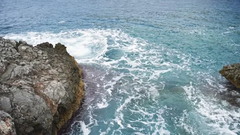 Waves crashing against rocks on a cloudy day Stock Footage 253786989