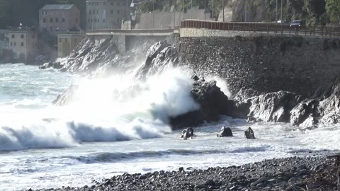Waves crashing against the rocky cliffs of the coast on a sunny day, along t Stock Footage 293360142